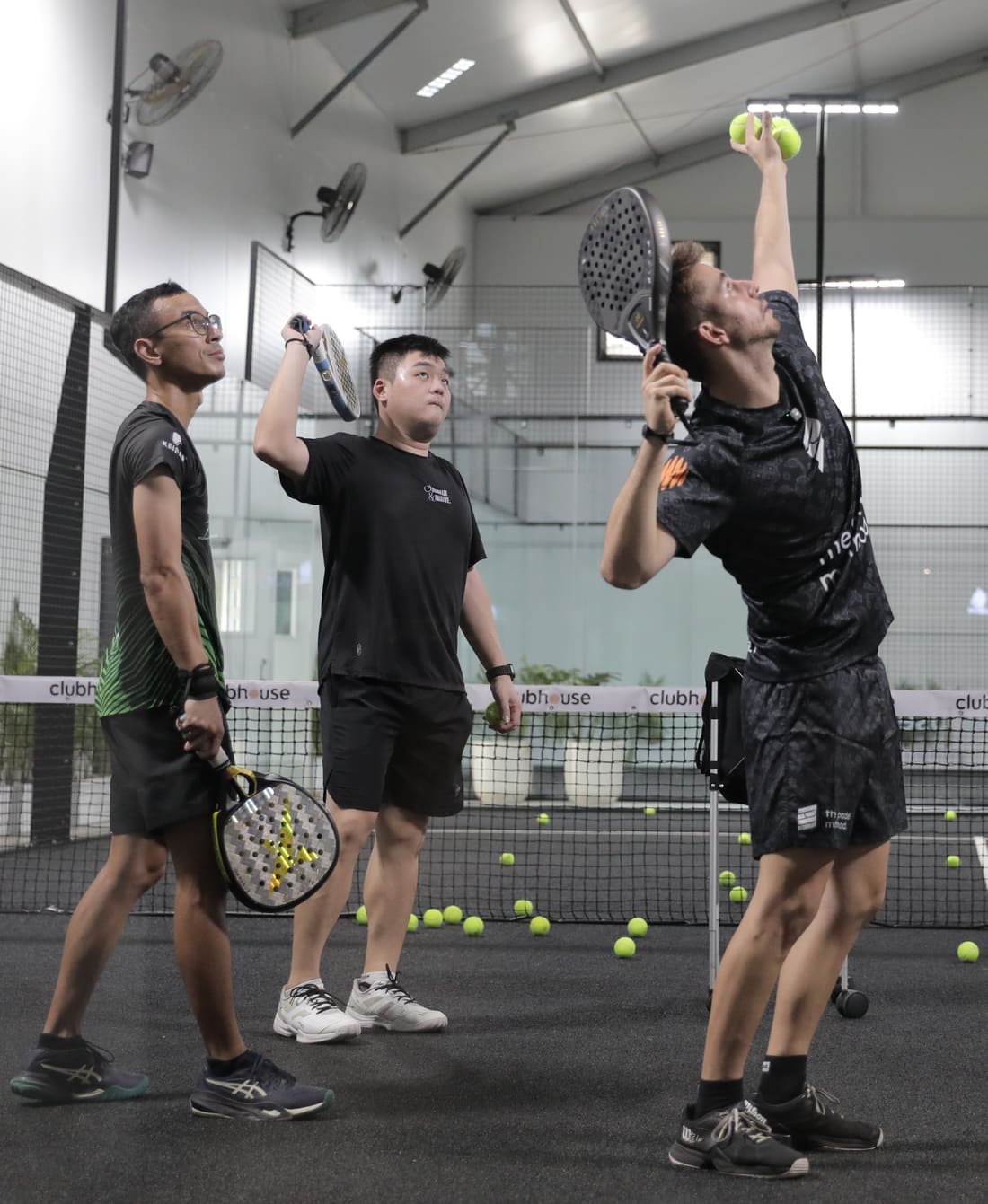 A coach showing a serve to two players on court in Jakarta